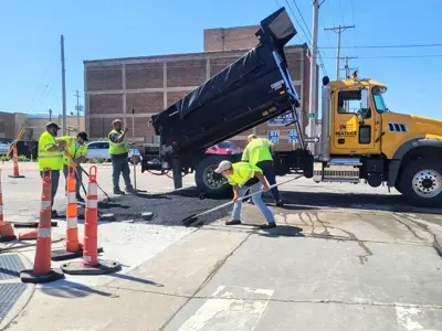 Workers installing asphalt paving on a street