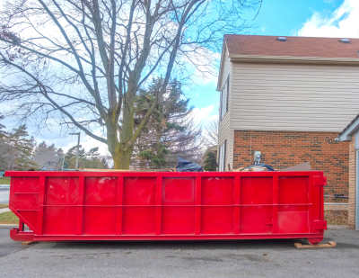 Red roll-off dumpster in residential driveway